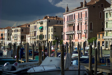 Fototapeta na wymiar Venice, ITALY: White boats near the Grand Canal, near Rialto s bridge with a few of wooden poles