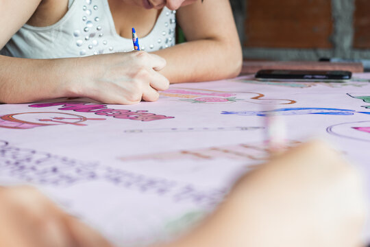 detailed view of a young latina college student. making a colorful poster before going out to march for her rights. girl making drawings with her colored pencils for the school expo.