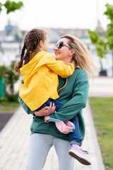 Fototapeta premium A girl of 5-6 years old on a walk with her mother. They socialize and have fun together. Family. Street. It's spring outside. Lifestyle.
