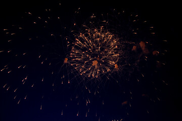 A bright ball of fireworks with orange sparks and a lot of sparks around on the background of the...