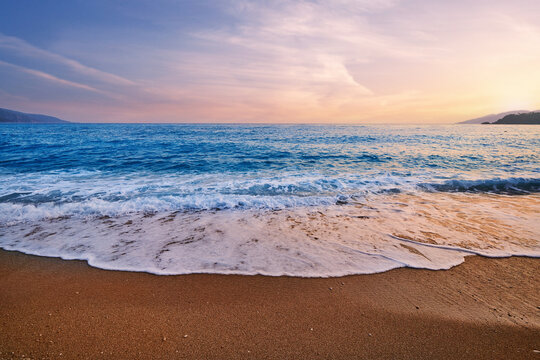 Landscape of gorgeous beautiful romantic idyllic blue turquoise sea with foam, gradient sky and sandy beach