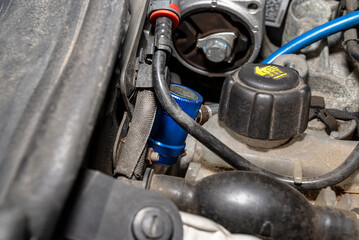 A blue quick-release coupler is installed on the valve from the air conditioning system in the car...