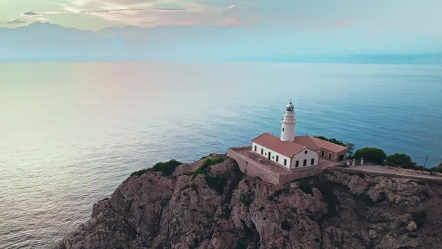 Scenic view of a Lighthouse during sunrise on a rocky coastline from above. Far de Capdepera in Carrer de sa Comassa, Majorca, Balearic Islands, Spain, the Lighthouse is Mallorca's easternmost point.
