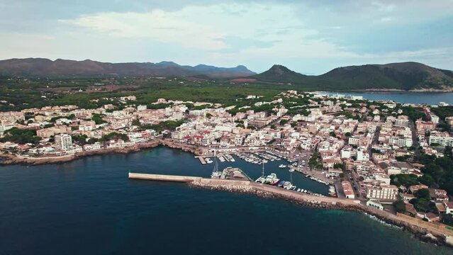 Panoramic view of a Spanish Town Port Cala Rajada with turquoise sea at sunset. Es Pelats and Cala Ratjada city from above in Majorca, Balearic Islands, Spain, drone view.