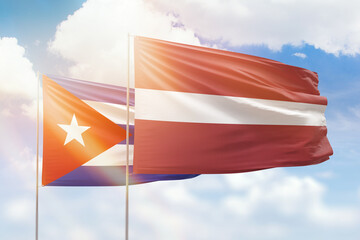 Sunny blue sky and flags of latvia and cuba