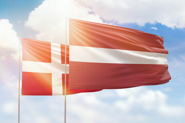 Sunny blue sky and flags of latvia and denmark