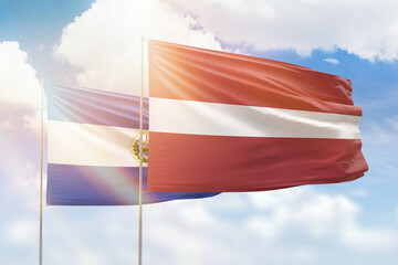 Sunny blue sky and flags of latvia and el salvador
