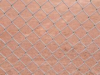 Close up of a chain-link fence with light brown dirt background