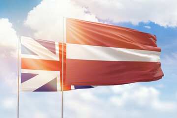Sunny blue sky and flags of latvia and great britain
