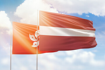 Sunny blue sky and flags of latvia and hong kong