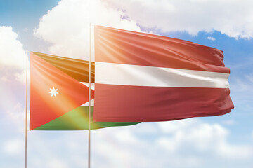 Sunny blue sky and flags of latvia and jordan