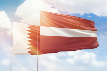 Sunny blue sky and flags of latvia and qatar