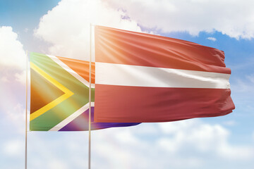 Sunny blue sky and flags of latvia and south africa