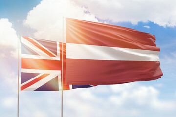 Sunny blue sky and flags of latvia and united kingdom