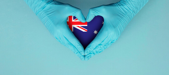 Doctors hands wearing blue surgical gloves making hear shape symbol with australia flag