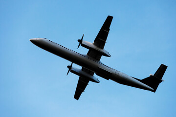 A large modern plane flies in the sky, a view from below from the ground to the belly of the aircraft.