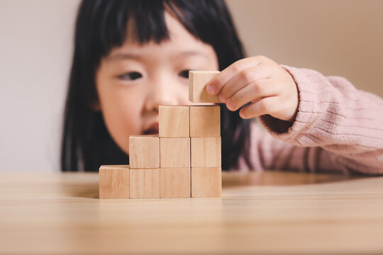 Asian kid stack small wooden block to stair. Concept for kid learning and child development.