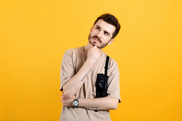 Caucasian young man wearing t-shirt posing isolated over yellow background thinking and touching chin while looking aside. Solution of problem. Looks up, makes up an idea.