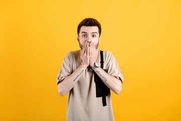 Caucasian young man wearing t-shirt posing isolated over yellow background shocked covering mouth with hands for mistake while. Secret concept. Looking at the camera.