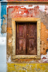 An artist and colourful looking wall with old brown window shutters