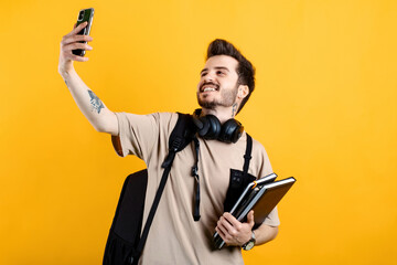 Young man smiling confident wearing beige tee posing isolated over yellow background university...