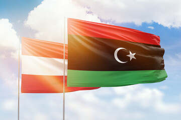 Sunny blue sky and flags of libya and austria