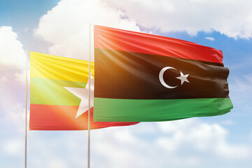 Sunny blue sky and flags of libya and myanmar