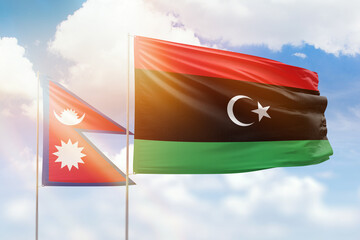 Sunny blue sky and flags of libya and nepal