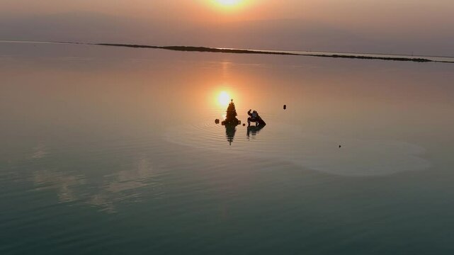 Santa Claus with Christmas tree in the sea water,aerial view
Beautiful shot from Dead sea Israel at sunset, Santa Claus sitting on chair on floating large chunk of salt, 2022,drone

