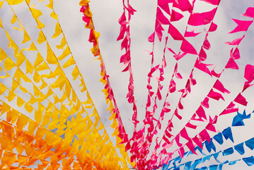 Colorful flags decorating the feast of Sao Joao against blue sky.