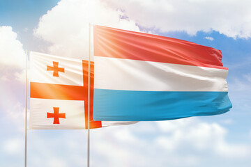 Sunny blue sky and flags of luxembourg and georgia