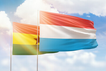 Sunny blue sky and flags of luxembourg and ghana