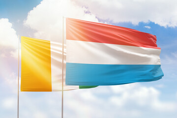 Sunny blue sky and flags of luxembourg and ivory coast