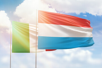 Sunny blue sky and flags of luxembourg and italy