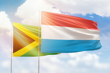 Sunny blue sky and flags of luxembourg and jamaica