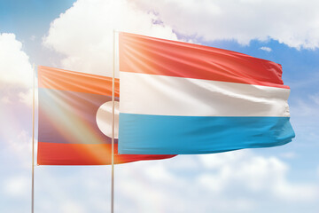 Sunny blue sky and flags of luxembourg and laos