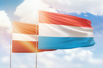 Sunny blue sky and flags of luxembourg and latvia