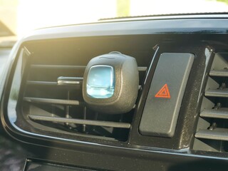 Perfume mount on an aircond vent of a car with emergency button.