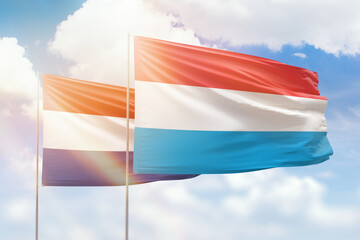 Sunny blue sky and flags of luxembourg and netherlands