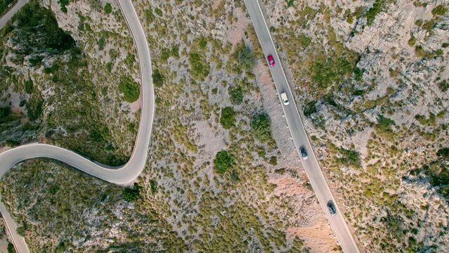 Cars, buses and motorcycles drive on European curved road in Majorca, Spain. Nus de Sa Corbata is a spectacular panoramic snake-like road with curves and rocky landscapes by the Mediterranean.