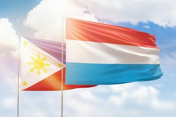 Sunny blue sky and flags of luxembourg and philippines