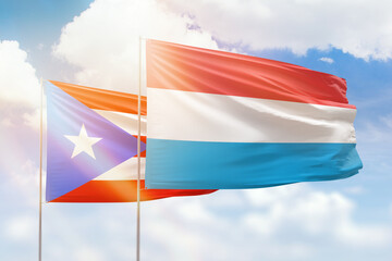 Sunny blue sky and flags of luxembourg and puerto rico