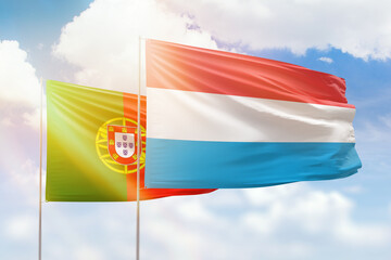 Sunny blue sky and flags of luxembourg and portugal
