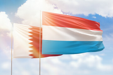 Sunny blue sky and flags of luxembourg and qatar