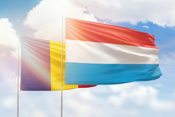 Sunny blue sky and flags of luxembourg and romania