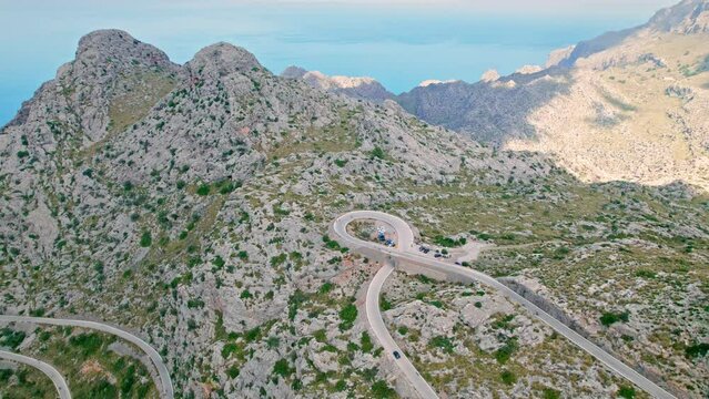 Cars, buses and motorcycles drive on European curved road in Majorca, Spain. Nus de Sa Corbata is a spectacular panoramic snake-like road with curves and rocky landscapes by the Mediterranean.