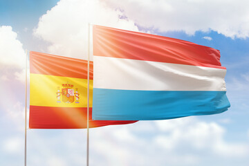 Sunny blue sky and flags of luxembourg and spain