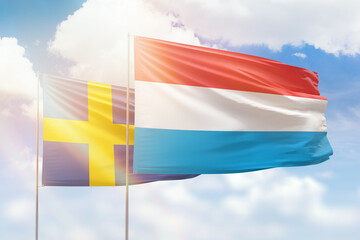 Sunny blue sky and flags of luxembourg and sweden