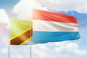 Sunny blue sky and flags of luxembourg and tanzania