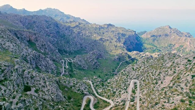 Cars, buses and motorcycles drive on European curved road in Majorca, Spain. Nus de Sa Corbata is a spectacular panoramic snake-like road with curves and rocky landscapes by the Mediterranean.